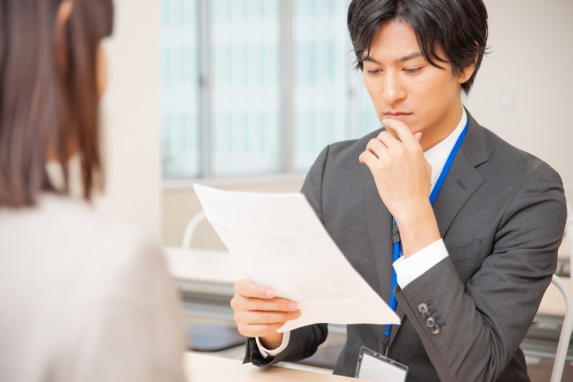 書類を手に俯いて考える男性
