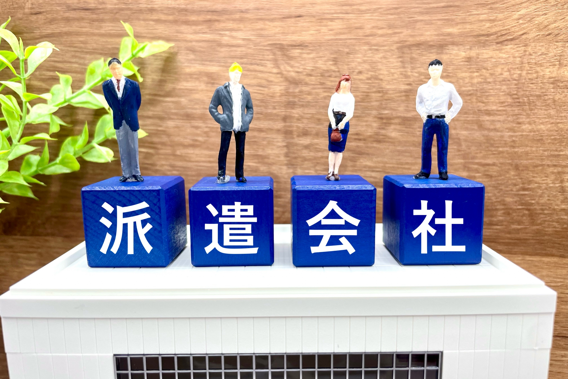 ビルの上に置かれた「派遣会社」の文字と派遣スタッフ
