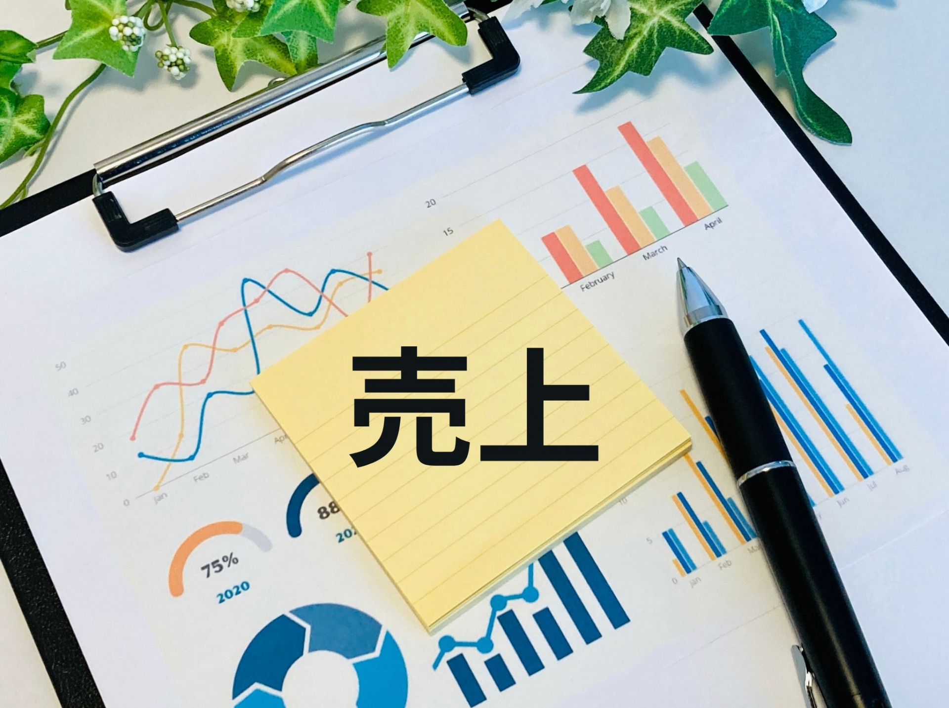 グラフが書かれた資料と「売上」の文字、ペン