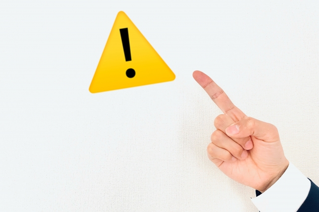 注意マークのアイコンを指差す手
