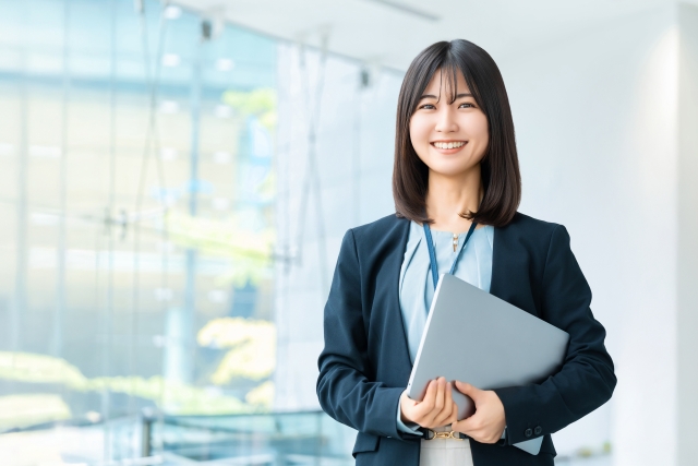 ノートパソコンを持った笑顔の女性
