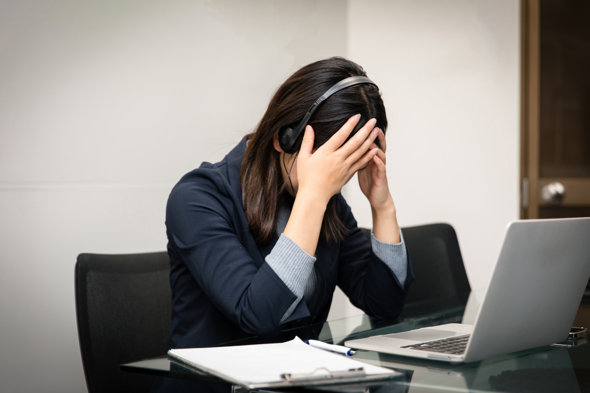 ノートパソコンを前に頭を抱え込むビジネスウーマン