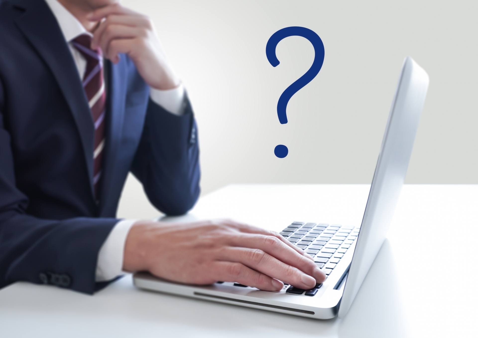 ノートパソコンを操作する男性とクエスチョンマーク